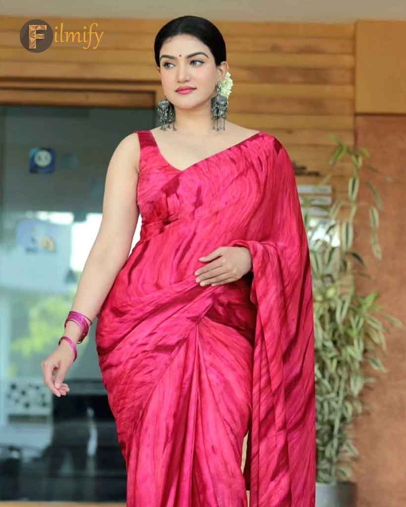 Honey rose appeared in a bright pinkish red saree paired with heavy earrings posing with her charming smile