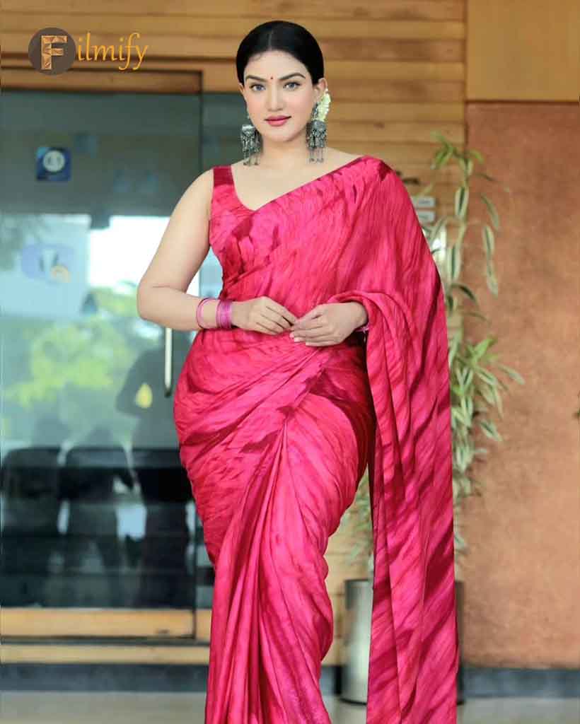 Honey rose appeared in a bright pinkish red saree paired with heavy earrings posing with her charming smile